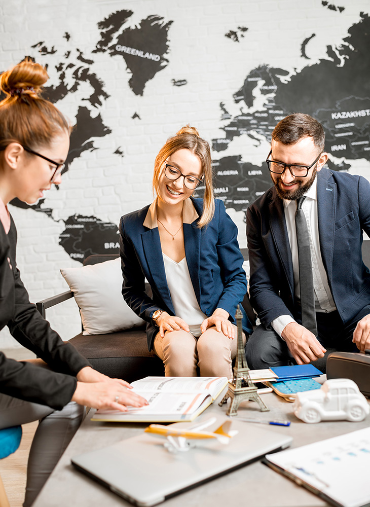 buisness associates sitting in front of a map on the wall, planning a trip
